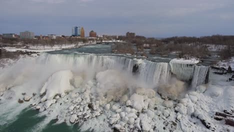 Niagara-Falls-and-icy-snowy-surroundings-in-winter,-wide-aerial-pan