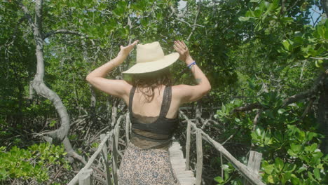 Medium-shot-of-a-woman-dancing-happily-on-a-wooden-bridge-in-a-green-forest