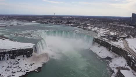 Misty-Horseshoe-Falls-at-winter-in-Niagara-Falls,-high-forward-aerial