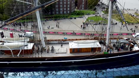 Cutty-Sark-ship-viewed-from-the-side,-tourist-people-walking-in-the-background,-aerial-shot,-United-Kingdom