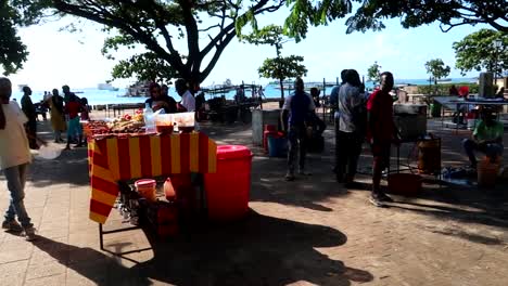Local-tanzanian-people-at-food-stalls-in-park-approaching-tourists-to-sell-typical-food
