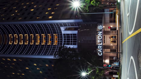 Ground-level-vertical-timelapse-of-busy-intersection-by-Carlton-Hotel,-Singapore