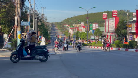 Busy-street-traffic-in-Vietnam-during-day-with-people-driving-mopeds,-cars-and-trucks