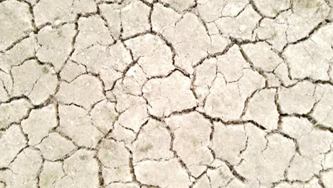 Dry-cracked-drought-fractured-land-aerial-view-flying-over-hot-barren-environment
