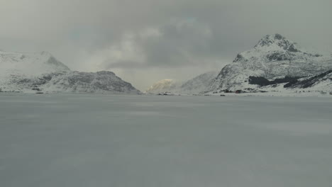 Drone-shot-of-a-frozen-lake-in-lofoten-with-mountains-in-the-background