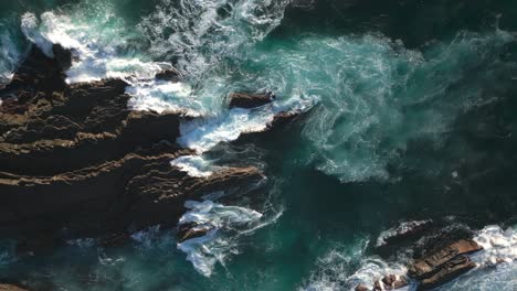 Ocean-cliffs-of-Portugal-coast,-rocky-reefs-and-crashing-waves,-drone-top-down-view