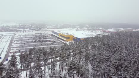 Popular-store-Ikea-disappearing-in-snowy-coniferous-forest,-dolly-back