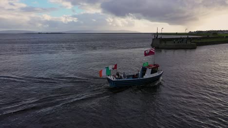 Drone-dolly-shot-of-a-traditional-fishing-boat-entering-the-Claddagh-dock-in-Galway,-Ireland
