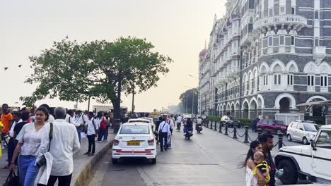People-walking-by-the-street-next-to-the-architectural-marvel-Taj-Mahal-hotel-In-Mumbai