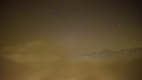 Low-valley-fog-at-nighttime-below-the-mountain-peaks---time-lapse-with-stars-in-the-sky