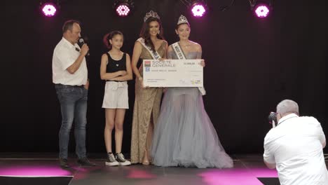 Hand-held-shot-of-the-Miss-France-winner-being-presented-with-her-cheque-on-stage