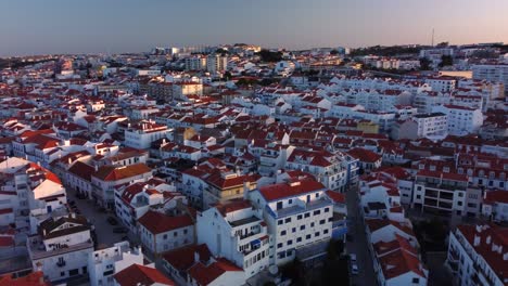 Aerial-Orbiting-shot-of-Ericeira-Downtown,-a-Portuguese-surfing-village-during-Morning-lights
