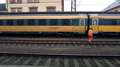 Zugführer-In-Einer-Reflektierenden-Orangefarbenen-Weste-Geht-Entlang-Der-Gleise-Im-Bahnhof