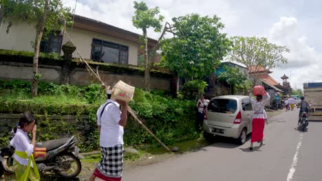 Traveling-on-a-scooter-through-Bali-village-as-a-traditional-ceremony-ends