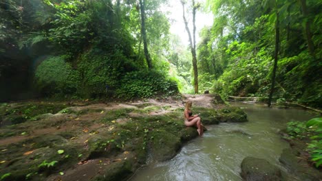 Hermosa-Mujer-Rubia-Relajándose-En-La-Naturaleza-De-Bali-Con-Una-Gran-Cascada-En-El-Fondo