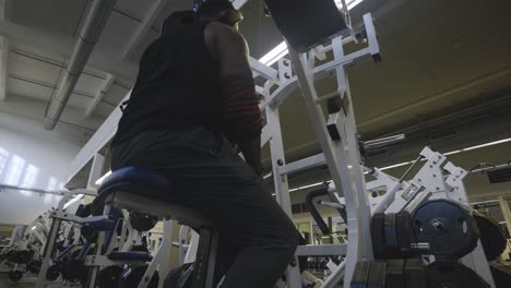 Black-Male-Bodybuilder-Strongman-Athlete-Preparing-Left-Hand-to-Train-Back-Muscle-On-Sports-Equipment-in-4K