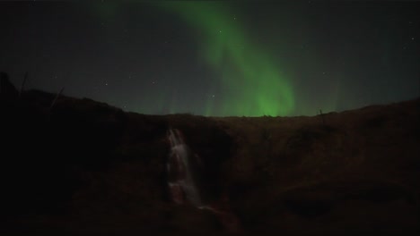 Faszinierende-Aurora-Borealis-Bei-Nacht-über-Dem-Wasserfall-Im-Skandinavischen-Land