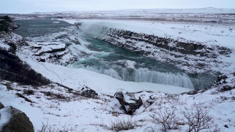 Static-wide-shot-on-top-of-mountain-showing-flowing-Gullfoss-Waterfall-in-Winter---Iceland,-Europe