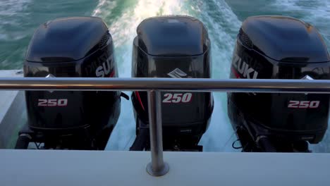 three-black-suzuki-outboard-engines-propelling-speedboat,-producing-wake