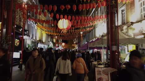 Walking-through-China-Town-in-London-at-night-during-the-Christmas-period-of-2022,-showing-crowds-of-people-in-the-lit-up-streets-and-street-decorations