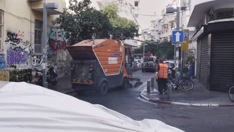 A-worker-in-a-bright-orange-uniform-operates-a-large,-powerful-city-cleaner-truck,-spraying-powerful-jets-of-water-to-quickly-wash-away-the-dirt-and-grime-from-the-streets