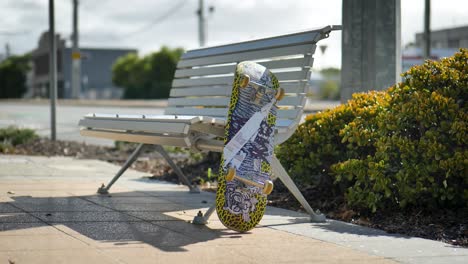 A-Skateboard-Sitting-on-a-Park-Bench-on-a-Sidewalk