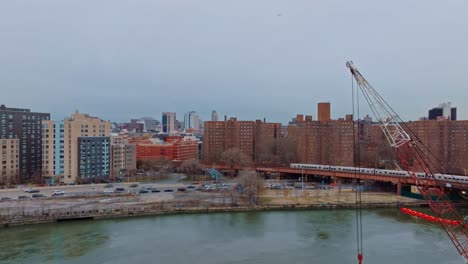 Rising-shot-of-crane-in-foreground,-projects-in-Harlem-in-New-York-City-4K-drone