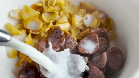Delicious-Breakfast:-Pouring-Hot-Milk-Over-Corn-Flakes-and-Chocolate-Flakes-in-White-Bowl---Close-Up-Shot