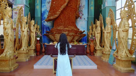 Woman-Worshipping-A-Giant-Female-Buddha-Statue-Made-Of-Immortal-Flowers-In-Linh-Phuoc-Pagoda,-Da-Lat-City,-Vietnam