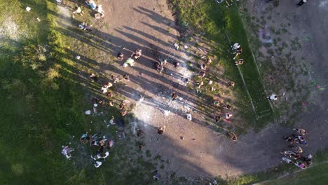 Aerial-top-down-shot-of-students-celebrating-graduation-outdoors-with-confetti-and-paint-bombs