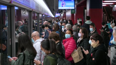 Commuters-wearing-face-masks-wait-patiently-for-a-subway-train-to-arrive-at-an-crowded-MTR-metro-station-in-Hong-Kong