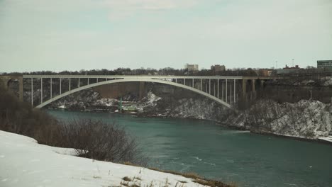 Rainbow-Bridge-by-snowy-Niagara-Falls-in-winter,-wide-static-view