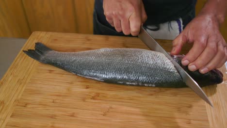 Chef-Cutting-Into-Fish-In-Kitchen