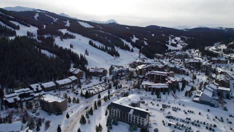 Drone-aerial-view-over-a-busy-ski-resort-with-cars,-hotels-and-condominiums