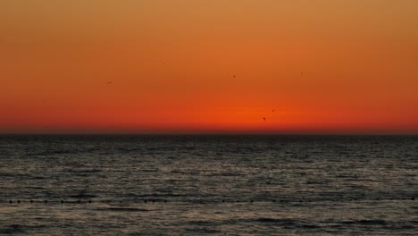 Static-shot-of-a-stunning-orange-sky-from-a-vibrant-sunset-over-the-ocean-in-Iquique