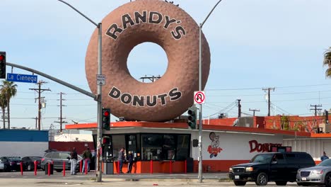 Wahrzeichen-Randy&#39;s-Donuts-In-Los-Angeles-In-Inglewood-Mit-Vorbeifahrendem-Verkehr-Auf-Dem-La-Cienega-Boulevard