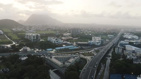 Cinematic-drone-shot-of-busy-highway-in-Mauritius-with-mountain-range-in-background-during-rainy-day