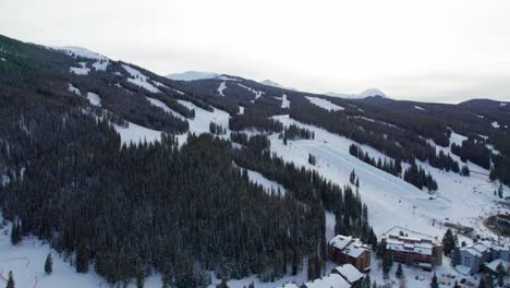 Aerial-drone-shot-of-ski-slopes-on-a-mountain-with-skiers-and-snowboarders