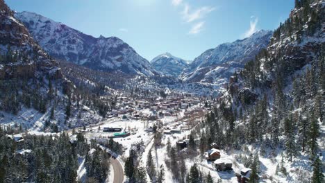 Panning-and-revealing-drone-shot-of-Ouray,-Colorado-on-a-bright-sunny-day