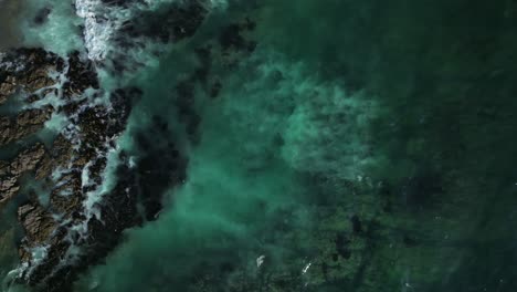Luftaufnahme-Von-Wellen,-Die-In-Iquique-Hereinrollen-Und-Gegen-Die-Felsen-Und-Das-Ufer-Krachen
