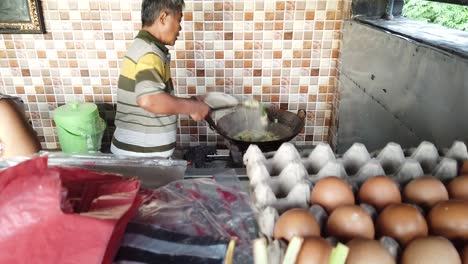 Indonesian-Chef-Cooking-Sauteed-vegetables-in-Bali-Cap-Cay-Local-Warung-Store-a-Family-Business-Husband-and-Wife-among-Hindu-Religious-Offerings