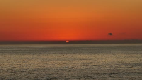 Luftaufnahme-Der-Dun-Einstellung-über-Dem-Horizont-Des-Ozeans-Mit-Einem-Leuchtend-Orangefarbenen-Himmel