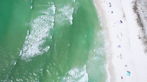 Drone-flying-over-clear-emerald-waters-of-the-Gulf-of-Mexico-with-people-on-white-sadey-bach
