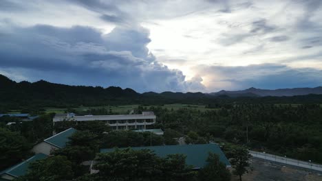 Aerial-Ascent-of-Village-with-Building-Cumulonimbus-Storm-Clouds-at-dusk,-Catanduanes,-Philippines