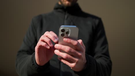 Man-in-a-black-jacket-working-on-a-new-smartphone-with-three-cameras