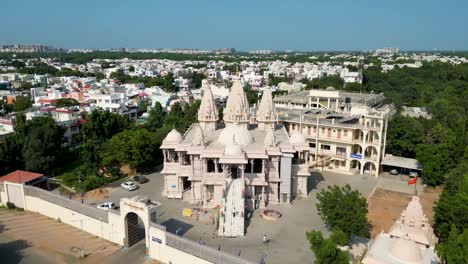Huge-Indian-Temple-in-a-city,-with-houses-around-it,-Swaminarayan-Temple,-Gandhinagar,-wide-Drone-shot-with-blue-sky
