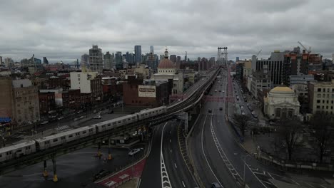 An-aerial-view-of-an-elevated-subway-train-in-Brooklyn,-NY,-heading-towards-Manhattan-on-a-cloudy-day