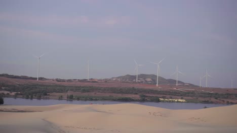 Windmills-spinning-in-the-desert-good-weather-from-White-Sand-Dunes-in-Mui-Ne,-Phan-Thiet,-Vietnam