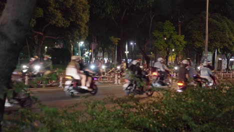 Vietnamese-Scooters-travelling-along-the-road-from-a-park-in-District-1-of-Ho-Chi-Minh-City,-Vietnam