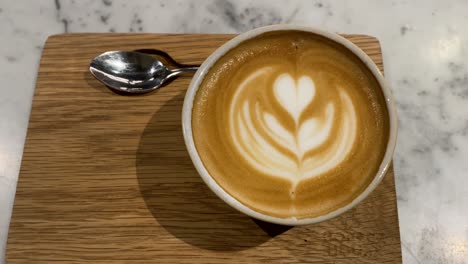 Nahaufnahme-Einer-Kaffeetasse-Mit-Fachmännisch-Gefertigter-Latte-Art-Darauf,-Dampfend-Und-Einladend